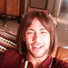 a man sitting on a couch with a drink in his hand and smiling at the camera