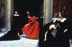 several women in black and red dresses are dancing on the stage with one woman wearing an orange dress