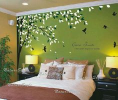 a bedroom decorated in green and white with birds flying over the tree wall decal