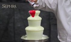 a man is decorating a white cake with red icing on it and the words sephora written in black