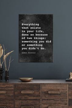 a black and white quote on a wall above a dresser with two vases in front of it