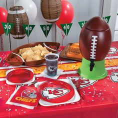 a football themed party table set up with plates, condiments and paper decorations