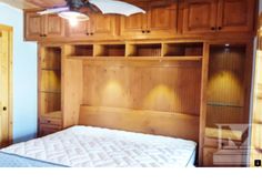 an empty bed in a room with wooden cabinets