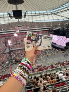 a person holding up a piece of paper in front of a stadium filled with people