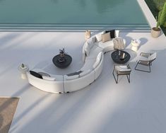 a white couch sitting on top of a patio next to a swimming pool with chairs and tables