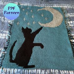 a black cat sitting on top of a blue and white blanket with stars in the sky