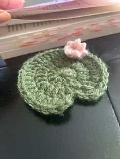 a green crocheted object sitting on top of a table next to some papers