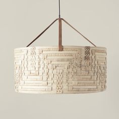 a light hanging from a ceiling fixture with woven material and wooden rods on the end