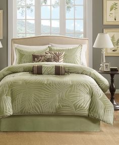 a bed in a bedroom with green comforter and pillows