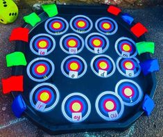 an outdoor game board with several different colored circles and numbers on it, sitting next to a yellow ball