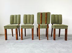 four green chairs sitting next to each other on top of a cement floor in front of a white wall