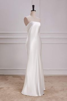 a white wedding dress on a mannequin in front of a plain wall and floor