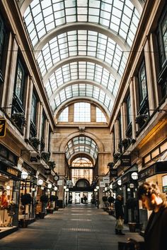 the inside of an indoor shopping mall with lots of windows and people walking through it