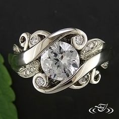 a white gold ring with diamonds and leaves on the side, in front of a black background