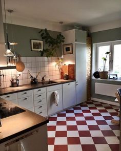 a kitchen with red and white checkered flooring next to a stove top oven