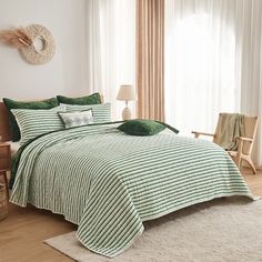 a bed with green and white striped comforter in a room next to a window