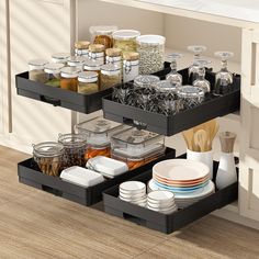 two black trays filled with dishes on top of a wooden floor next to a counter