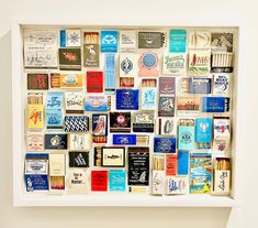 a white frame filled with lots of different types of cards and magnets on the wall