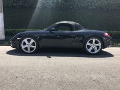 a black sports car parked in front of a hedge