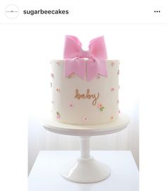 there is a white cake with pink bows on it and the words baby spelled in gold