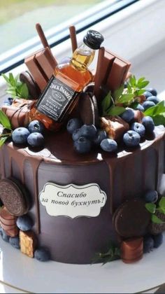 a chocolate cake decorated with blueberries, cookies and an alcohol bottle on the top