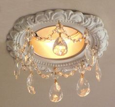 a white light fixture with crystal drops hanging from it's center and the lights on either side