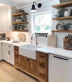 a kitchen with white cabinets and wooden shelves filled with dishes on top of the counter