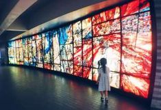 a woman is standing in front of a large display of colorful images on the wall