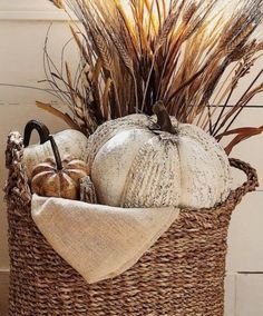 a basket filled with white pumpkins and dry grass