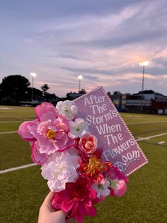 someone holding up a sign with flowers on it that says after the storm, when the flowers bloom