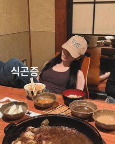 a woman sitting at a table with bowls of food and chopsticks in front of her