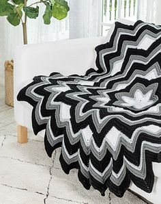 a black and white blanket sitting on top of a couch next to a potted plant