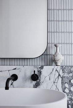 a white sink sitting under a bathroom mirror next to a wall mounted faucet