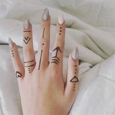 a woman's hand with tattoos on her fingers and thumbnails in the shape of arrows