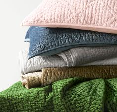 a stack of blankets and pillows sitting on top of each other