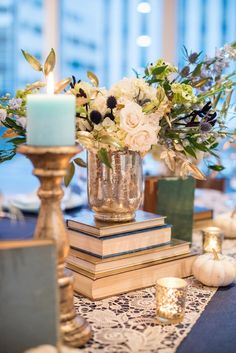 a table topped with books and flowers next to a candle