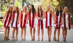 a group of young women standing next to each other wearing red and white graduation gowns