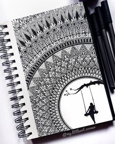 a spiral notebook with a drawing of a girl on a swing and two black pens next to it