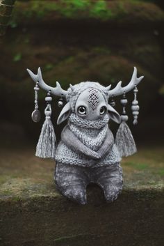 a small statue with horns and tassels on it's head sitting on the ground