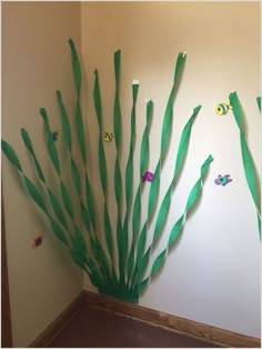 a room with some green grass and fish on the wall next to it is decorated with paper streamers