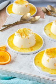 four desserts with orange slices and spoons on a table