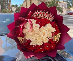 a bouquet of roses with a tiara on the hood of a car in front of a building