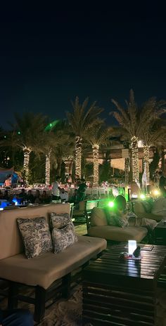 an outdoor seating area at night with palm trees in the background