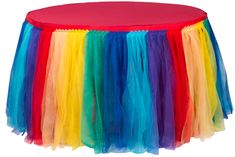 a rainbow colored table cloth on top of a red tablecloth with multicolored tulle