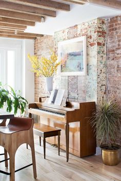 a living room with a piano and potted plant in the corner next to it