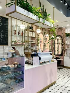 the inside of a restaurant with plants hanging from the ceiling and shelves on the wall