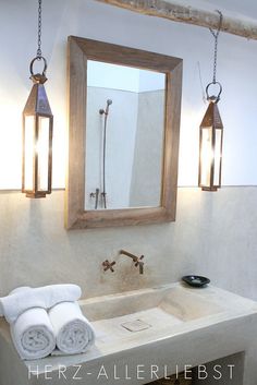 a bathroom with a sink, mirror and two lights hanging from the ceiling above it