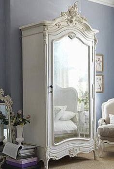 an ornate white armoire in a room with blue walls and carpeted flooring