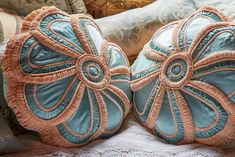 two decorative pillows sitting on top of a bed