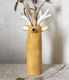 a vase with flowers in it and a deer's head sticking out of it